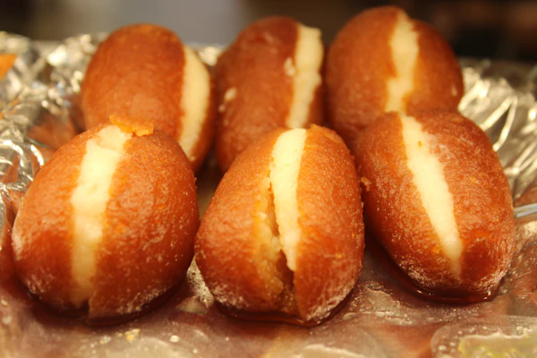 Brown gulab jamun split open and filled with white cream.